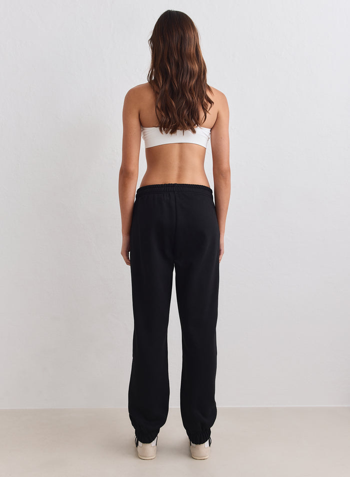 Mustat aim'n Classic Sweatpants pehmeää harjattua jerseytä resorilahkeilla kuvattuna takaa. [S-163cm]