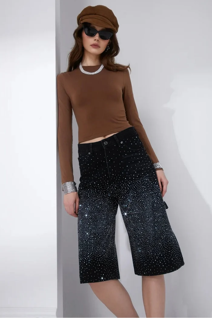 Black washed denim Bermuda shorts with allover crystal stud embellishment and classic five-pocket styling.