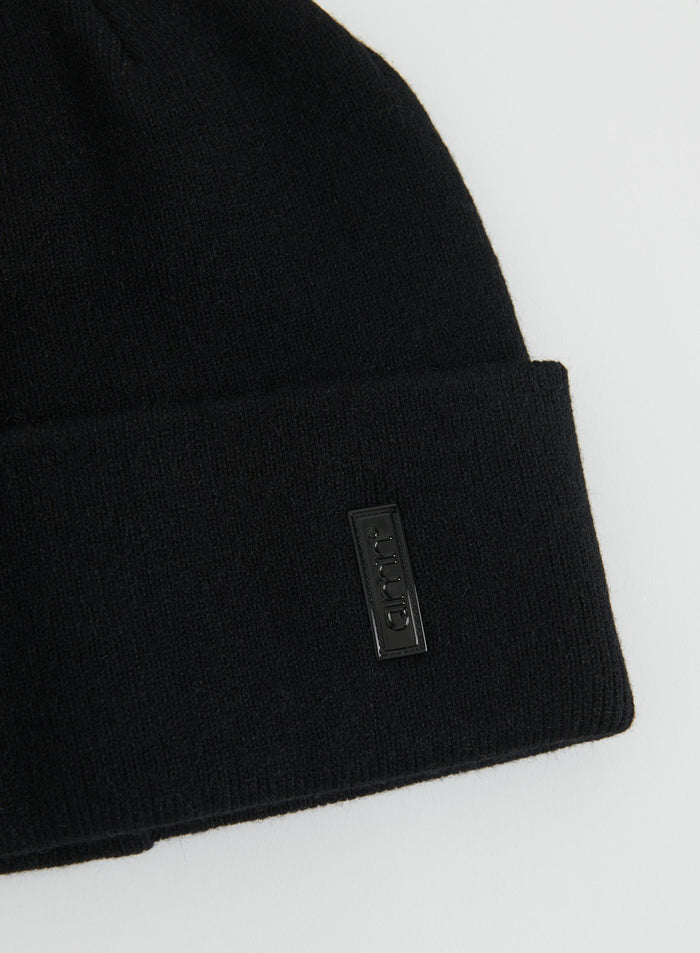 Lähikuva mustasta neulotusta Outdoor Logo Beanie -piposta, jossa on taitettu käänne ja aim'n-logomerkki