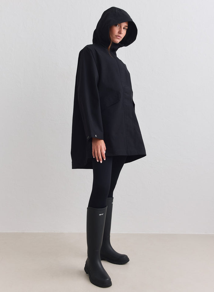 Musta aim'n Waterproof Hood Jacket puettuna yhteensopivien leggingsien ja korkeiden kumisaappaiden kanssa. [M-178cm]
