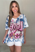 Blush Love Script Graphic Knit Top with a V-neck, short sleeves, pink floral heart LOVE graphic, and blue abstract lettering background.