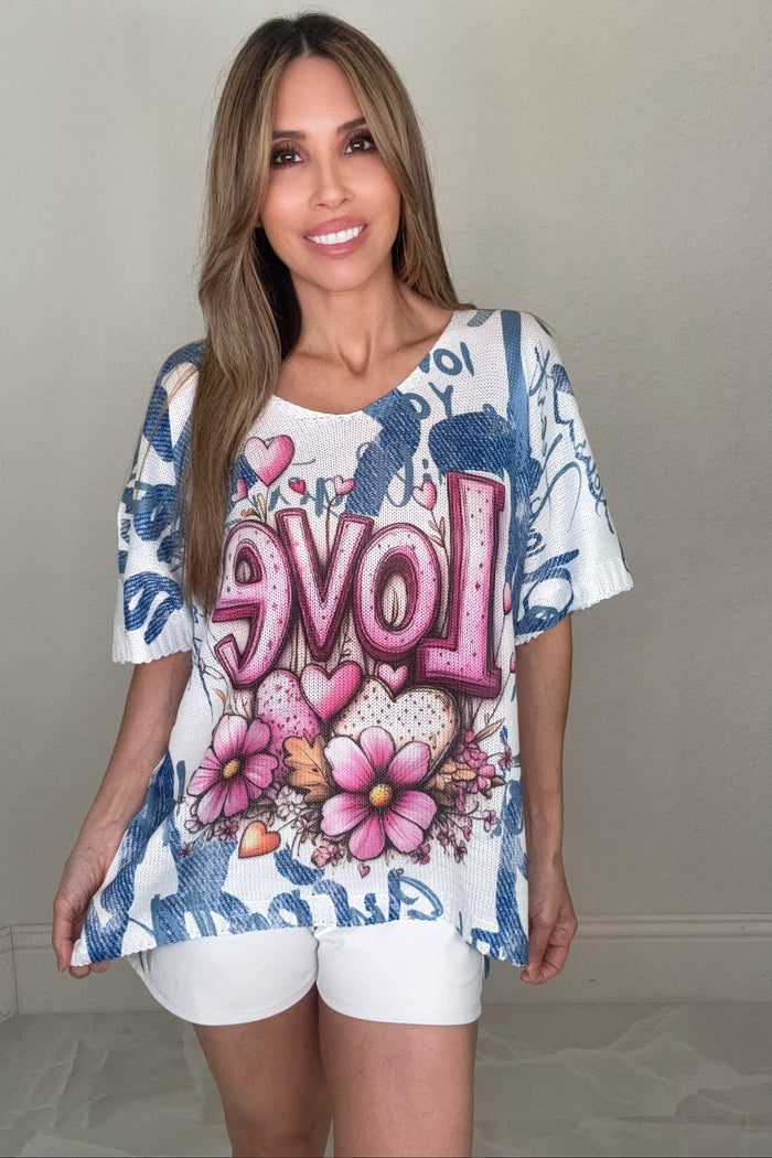 Blush Love Script Graphic Knit Top with a V-neck, short sleeves, pink floral heart LOVE graphic, and blue abstract lettering background.
