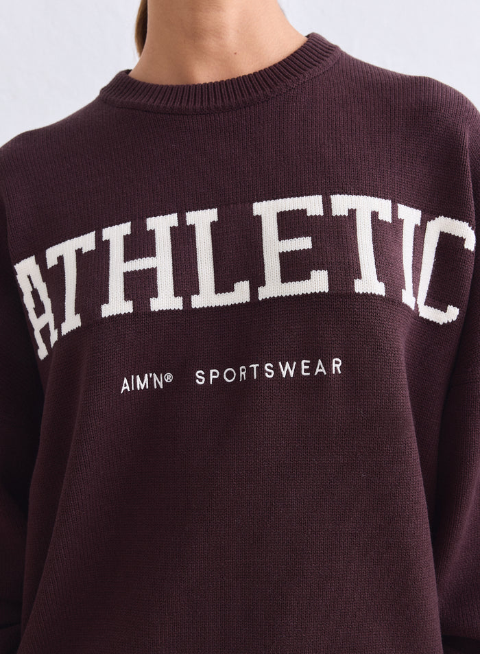Lähikuva suklaanruskeasta aim'n Athletic Knit Sweatshirt -neulepaidasta valkoisella logolla [S-165cm]