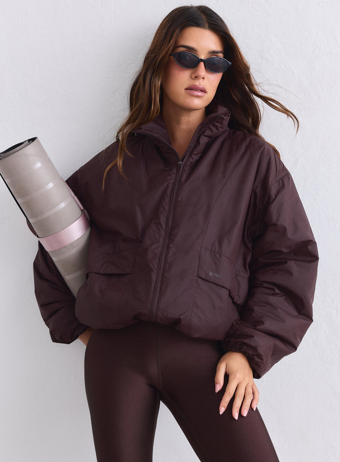 Suklaanruskea aim'n Cloud Jacket, ruskeat leggingsit ja rullattu joogamatto. [S-165cm]