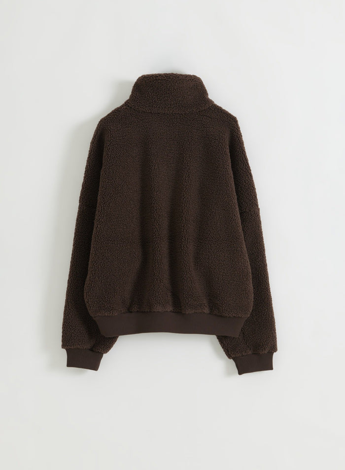 Suklaanruskea pilefleece-puolivetoketjullinen takki kuvattuna takaa flat lay -asetelmassa