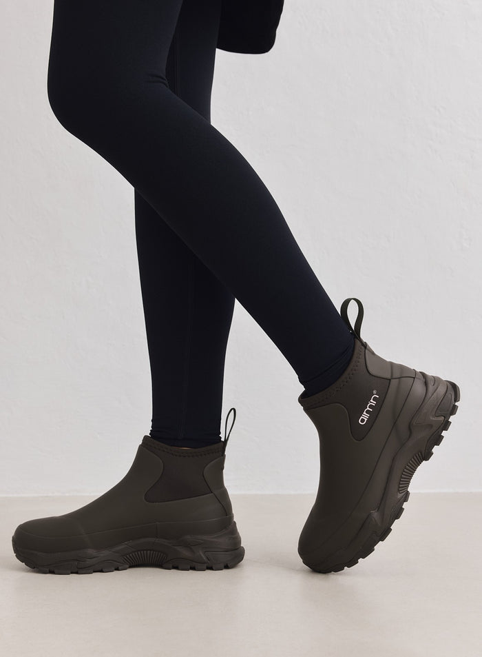 Dark Ivy Chelsea-tyyliset aim'n Fusion Rain Boot -kumisaappaat paksulla lenkkaripohjalla ja mustat leggingsit.