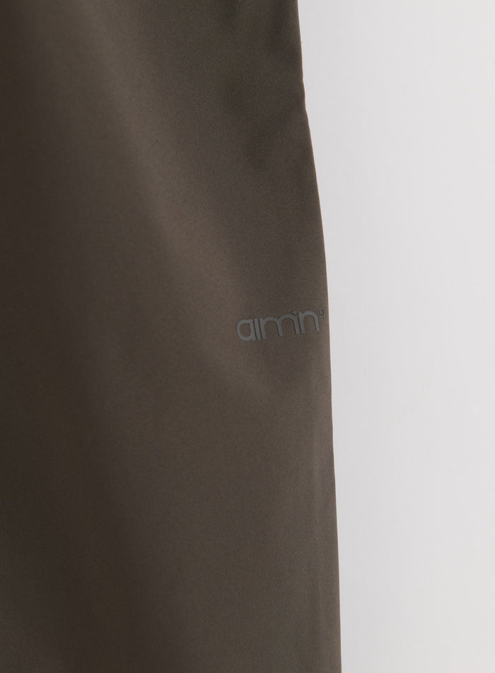 Lähikuva Dark Ivy Waterproof Pants -housujen kankaasta, jossa näkyy aim'n-logo