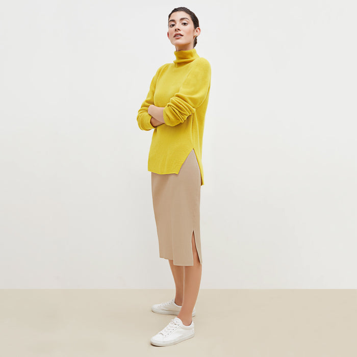 Side image of a woman standing wearing the Harlem skirt in latte