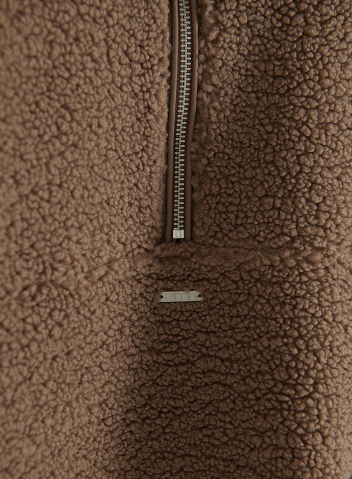 Lähikuva hazelnut pile half-zip -fleecepaidasta, jossa näkyy vetoketju ja aim'n-metallilogolappu