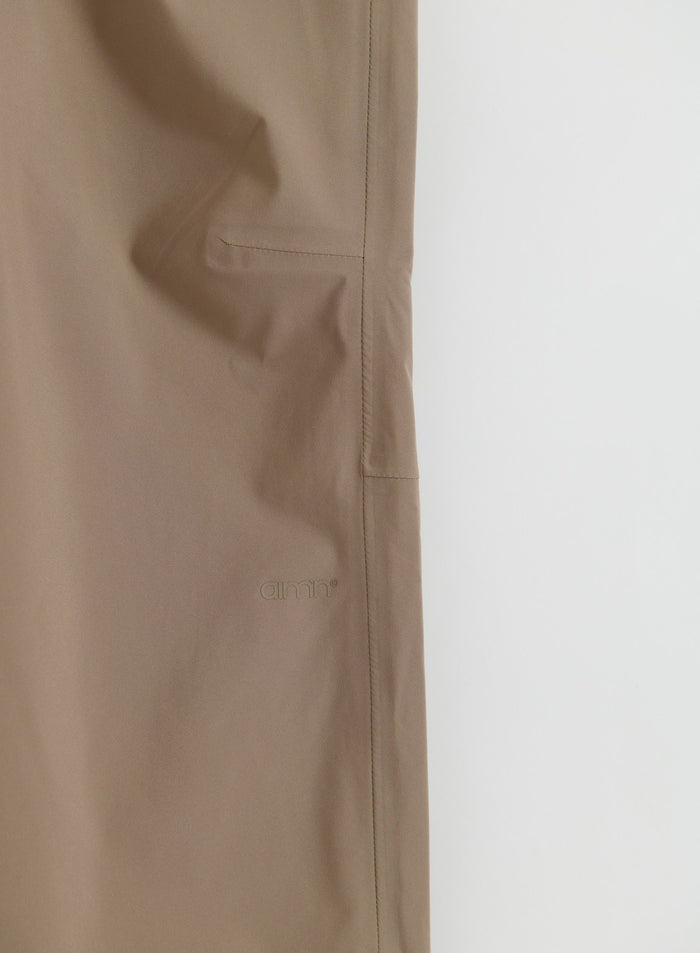 Lähikuva aim'n Hazelnut Waterproof Pants -housuista, joissa näkyy taskun yksityiskohta ja logo