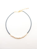 A dark blue beaded necklace with elegant white pearls, featuring an adjustable gold-colored chain.