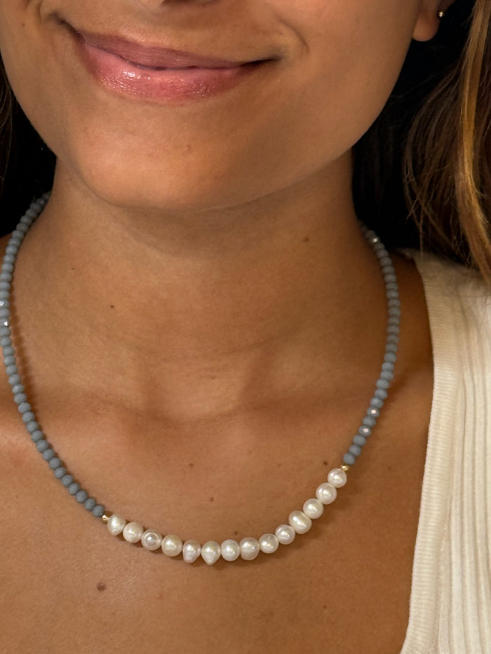 A pale blue necklace with pearls showed on a model