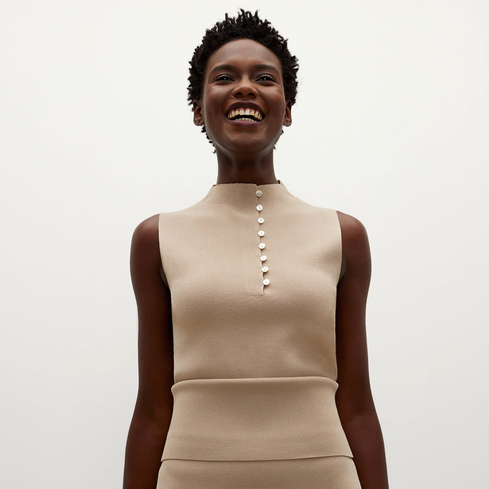 Front image of a woman standing wearing the Malki top in latte