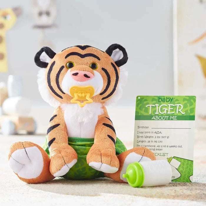 Baby tiger soft toy animal with pacifier in its mouth, wearing a green nappy, beside a baby bottle and card