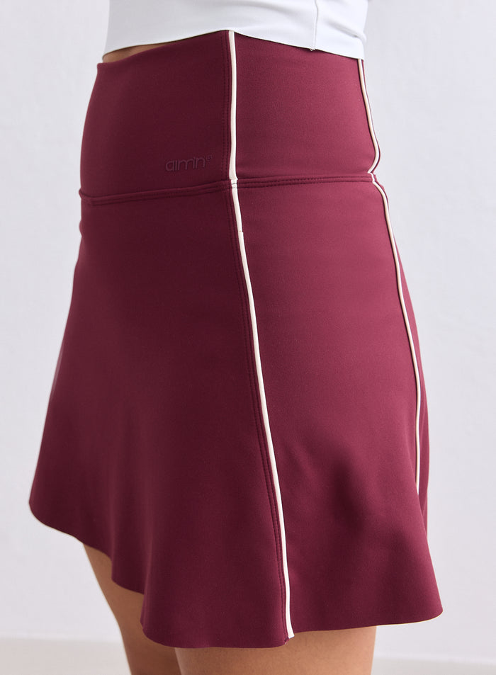 Korkeavyötäröinen merlot-värinen aim'n Sense Contrast Skort valkoisilla pystytereillä. [XS-165cm]