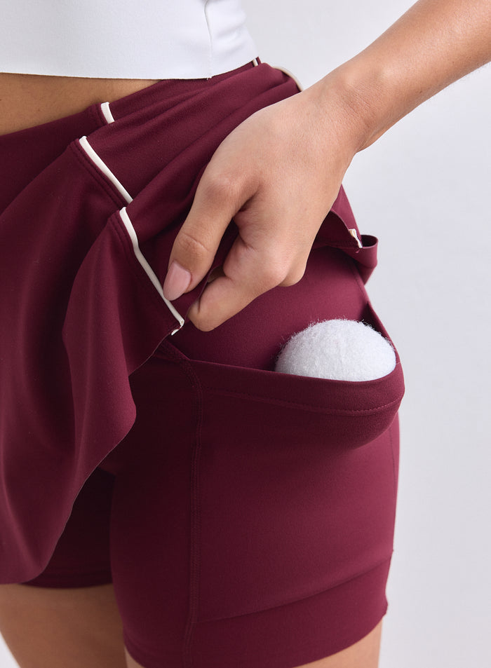 Merlot-värinen aim'n Sense Contrast Skort valkoisilla tereillä ja sisäshortseilla, joissa on tennispallo. [XS-165cm]
