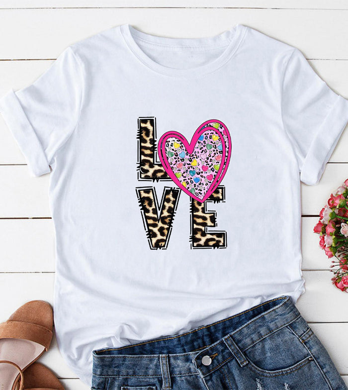 White crewneck graphic tee with a leopard print design and pink heart accent on the front.