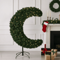 crescent moon shaped tree in contemporary room beside fireplace with gifts in front