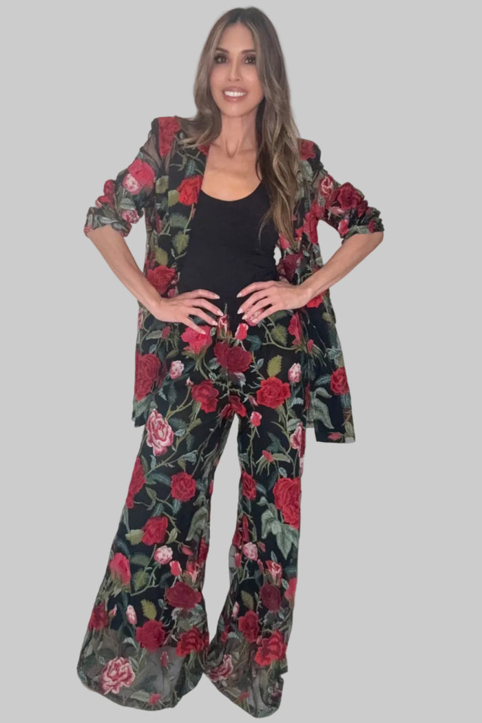 Red floral lace flare pants with a bold red, green, and black pattern and flowing wide leg silhouette.