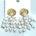 White beaded earrings featuring a golden shell-shaped detail for a coastal-inspired boutique jewelry look.