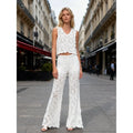White crochet floral sleeveless tank top with open floral pattern, worn on a city street.