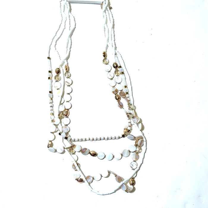 White and gold multilayered shell necklace with draped strands, white shell accents, and shiny gold bead details.