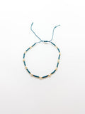 An adjustable teal bracelet with gold accents on a white background